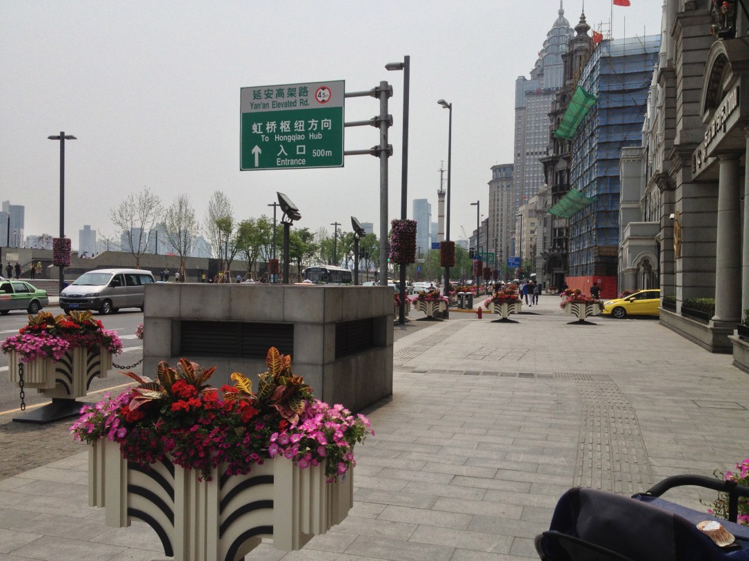 Flowers line the street that is next to the Bund. 